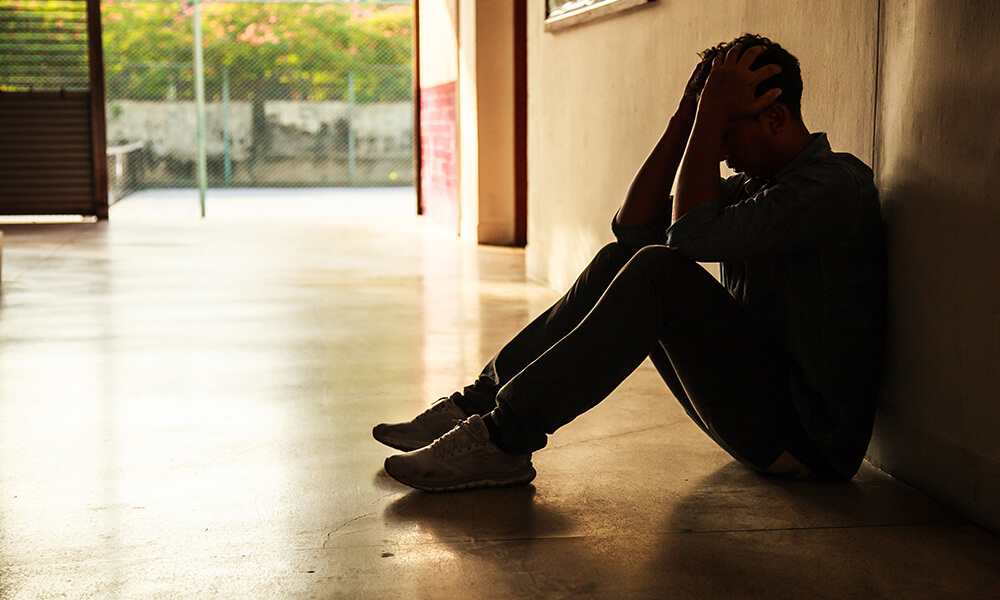 man sitting on floor with head in hands in crisis