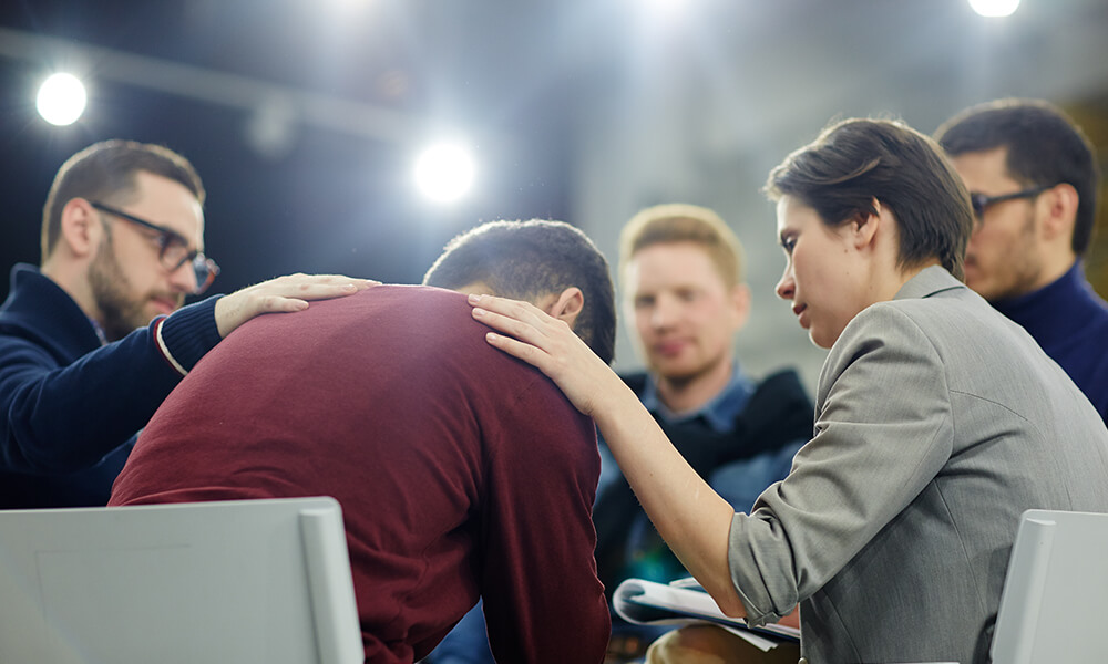 group of adults sitting in a circle showing emotional support for a friend